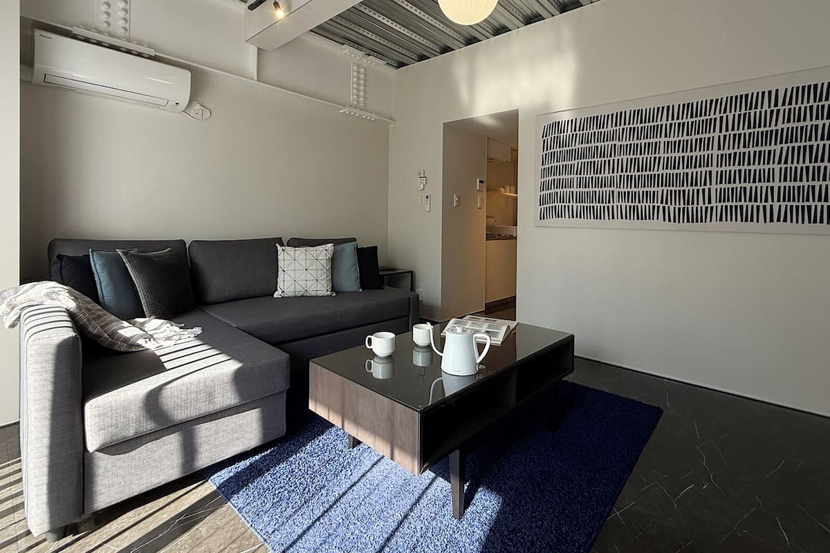 A modern living room with a sofa, coffee table, and a wall-mounted abstract art piece.