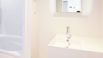 A bathroom with a white sink, mirror, and shower.