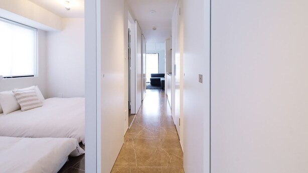 Un pasillo de hotel con una cama a la izquierda y una zona de estar al fondo.