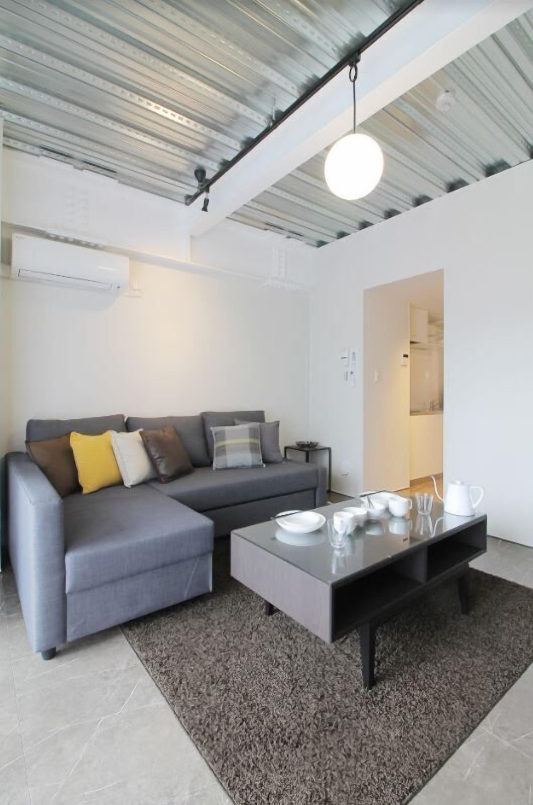 A modern living room with a grey sofa, a coffee table, and a rug.