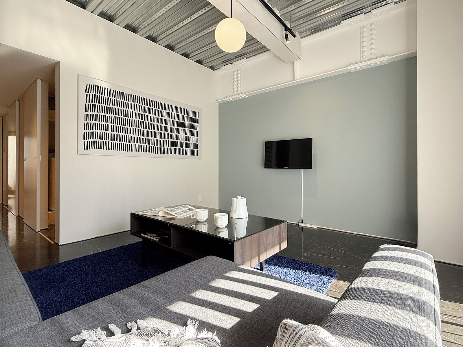 Una sala de estar moderna con un sofá, una mesa de centro y un televisor de pantalla plana montado en la pared.