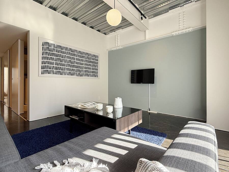 Un salon moderne avec un canapé, une table basse et un téléviseur à écran plat fixé au mur.
