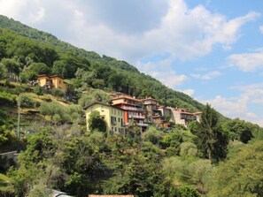A hillside with multiple buildings, likely residential, surrounded by lush greenery and trees. - Ca' Pia by Interhome (San Siro)