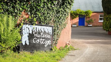 Experience the charm of Wisteria Cottage, a classic country home surrounded by lush greenery.