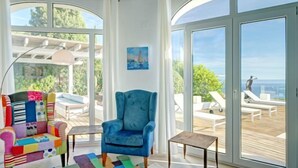 A spacious room with a large window, a blue armchair, a colorful sofa, and a small table. - Villa Terrace sur Mer by Interhome (Jávea)