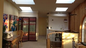 Ein Zimmer mit Dachfenstern, einem Essbereich mit Tisch und Stühlen sowie einer Küchenzeile mit Kühlschrank und Mikrowelle.