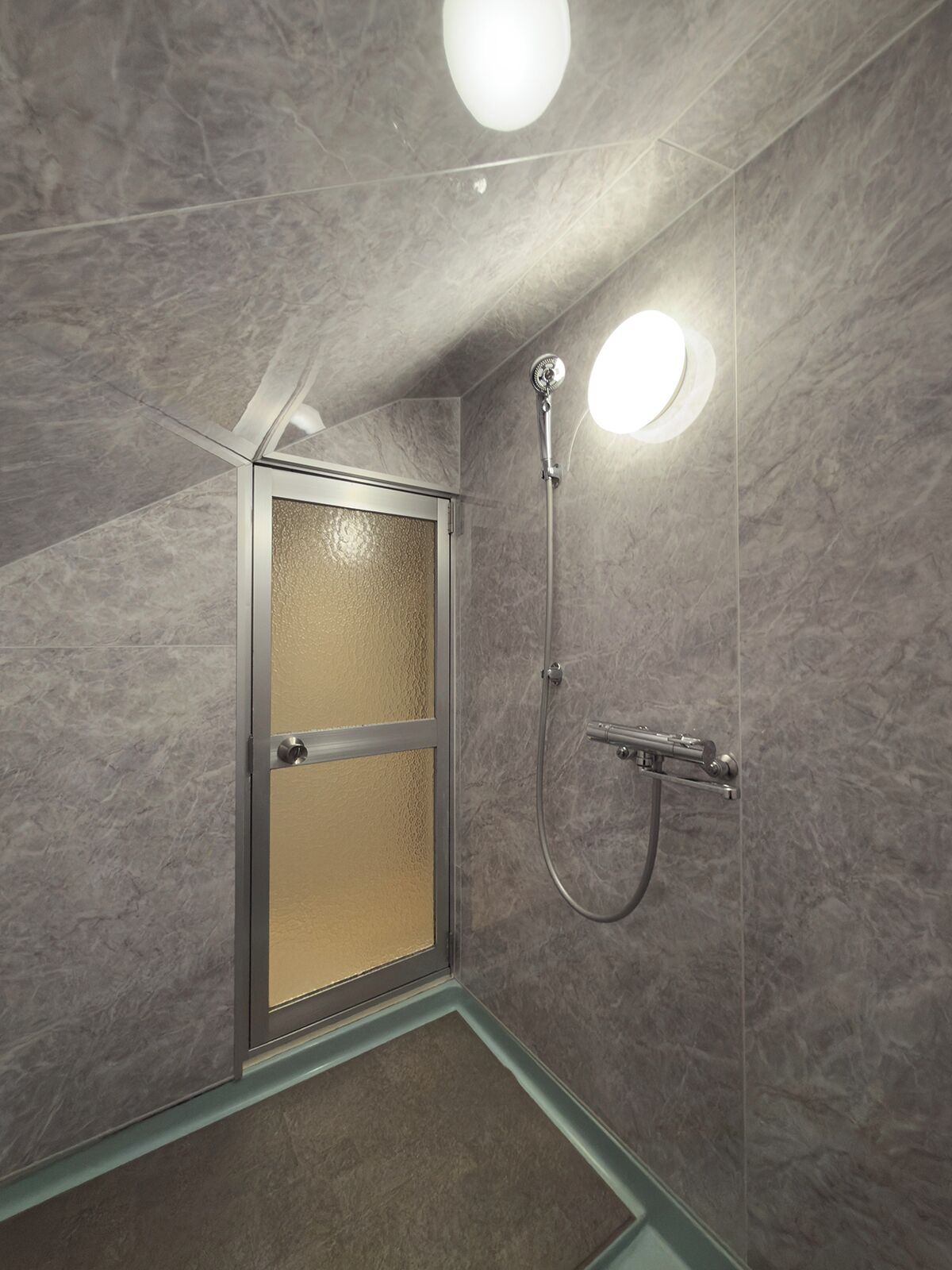 Ducha con puerta de cristal y cabezal de ducha de mano.