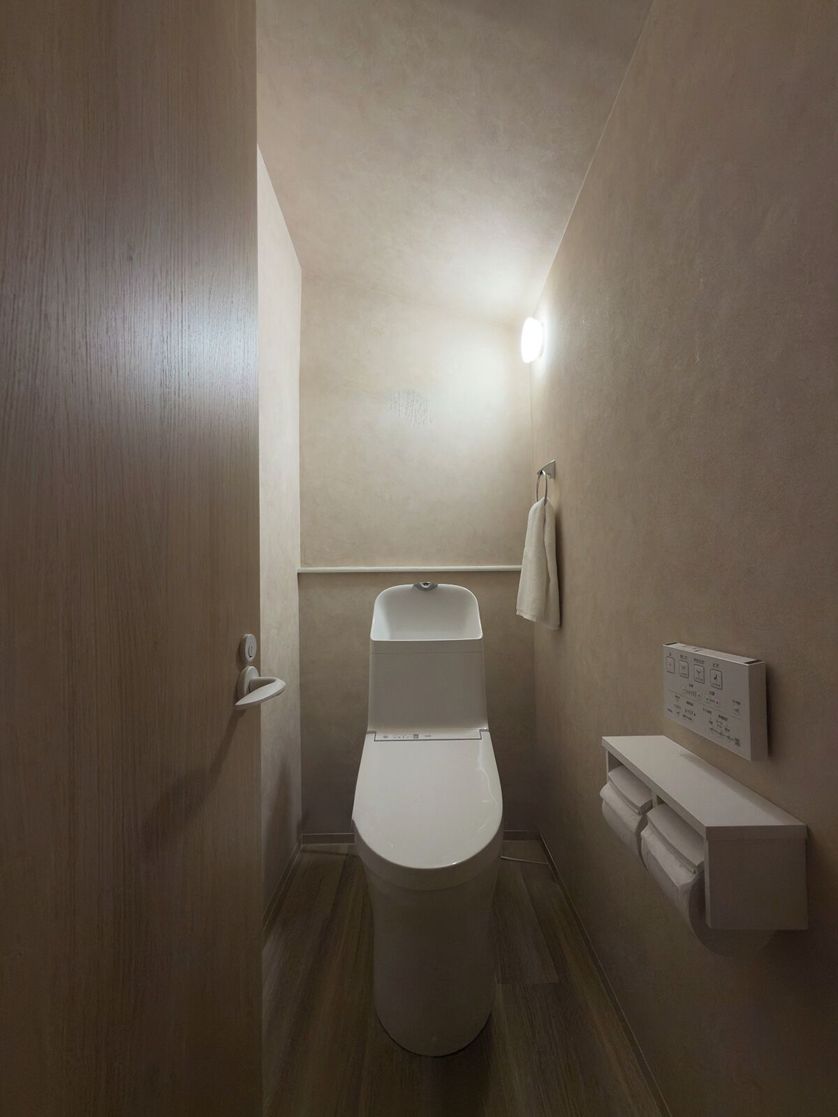 Une salle de bain moderne équipée de toilettes, d’un porte-serviettes et d’un support à papier toilette.