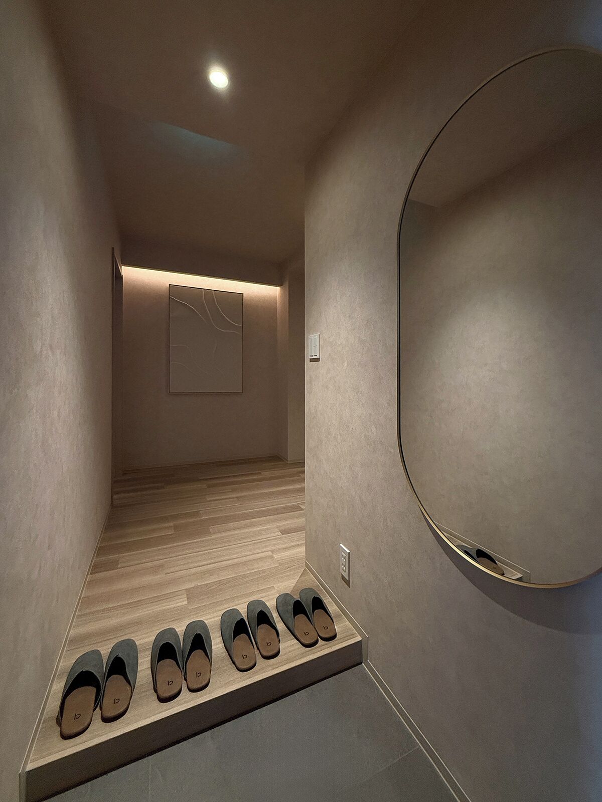 A hallway with a shoe rack, a wall-mounted mirror, and a recessed ceiling light.