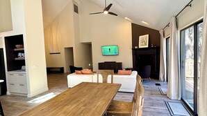 A spacious living room with a wooden dining table, a sofa, and a TV mounted on the wall. - Hoof Haus in Aspen Valley Country Club in Flagstaff (Flagstaff)