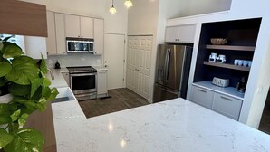 A modern kitchen with white cabinetry, a marble countertop, stainless steel appliances, and pendant lighting. - Hoof Haus in Aspen Valley Country Club in Flagstaff (Flagstaff)