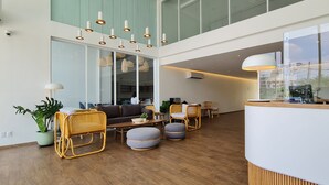A spacious lobby with a wooden floor, a reception desk, and seating areas with rattan chairs and ottomans. - Mintel Huamark (Bangkok)