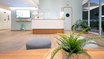 A modern reception area with a wooden reception desk, a large flat-screen TV, and a reception counter.