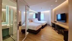 A modern hotel room with a glass shower enclosure, two beds, a desk with a chair, and a TV on the wall. - Mintel Huamark (Bangkok)