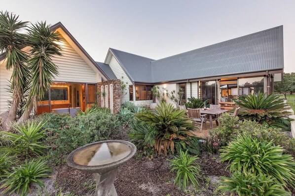 A modern house with a patio, outdoor seating, and a variety of plants.