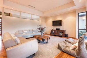A modern living room with a sofa, a coffee table, a TV, and a large window.