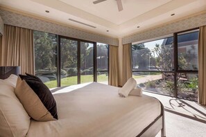A hotel room with a large bed, a ceiling fan, and a view of the outdoors.