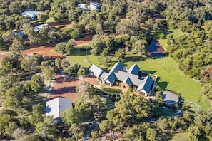 A large estate with multiple buildings, surrounded by dense trees and a small water body.
