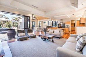 A modern living room with a sofa, coffee table, and a view of the kitchen.