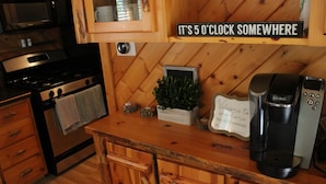 A kitchen with wooden cabinets, a stove, a microwave, and a Keurig coffee maker.