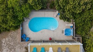 En vy från ovan över ett poolområde med en terrass, solstolar och en bubbelpool.
