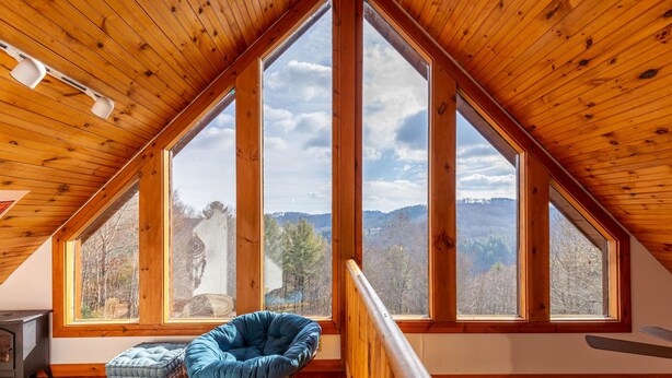 Ein gemütliches Dachzimmer mit einem großen Schiebedach, einem Schaukelstuhl und Blick auf die umliegende Landschaft.