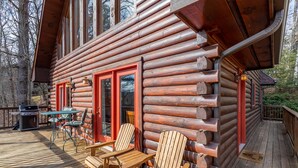 Eine Blockhütte mit einer Terrasse, Sitzgelegenheiten im Freien und einem Grill.