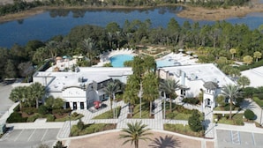 Ett flygbildsbild av ett semesterområde med en swimmingpool, palmer och en sjö.
