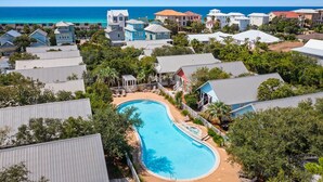 Un resort con piscina central, rodeado de edificios y abundante vegetación.
