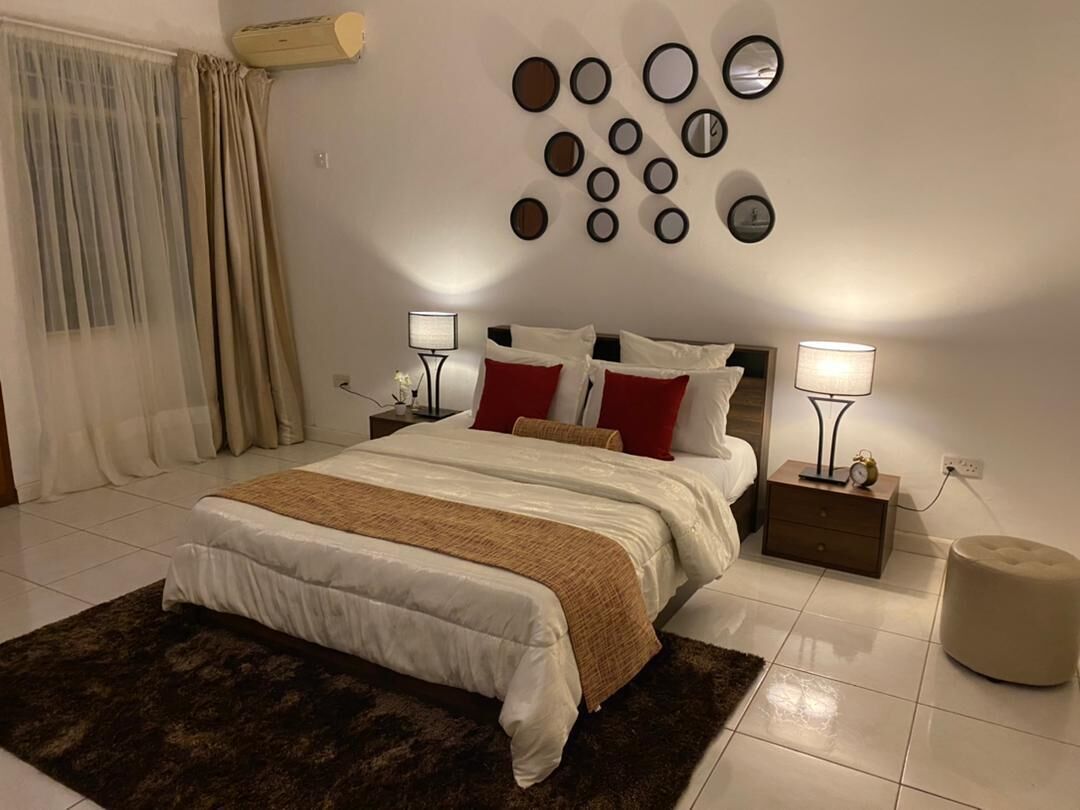 A bedroom with a bed, bedside tables, a wall-mounted mirror, and a rug.