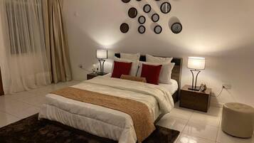 A bedroom with a bed, bedside tables, a wall-mounted mirror, and a rug.