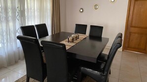 A dining area with a rectangular table, six black chairs, and three wall-mounted decorative mirrors. - Cozy 3BR home - gated estate - Tema - top security (Tema)