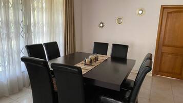 Un'area pranzo con un tavolo rettangolare, sei sedie nere e tre specchi decorativi fissati alla parete.