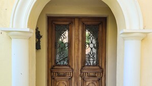 Une porte à deux battants en bois, dotée de panneaux de verre et d’un seuil décoratif en métal.