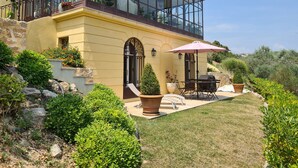 Une maison à deux étages dotée d’une véranda, d’un espace extérieur aménagé et d’un jardin bien entretenu.