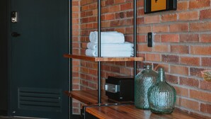 A room with a brick wall, wooden shelves, and a mirror.