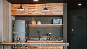 A modern kitchen with a wooden backsplash, stainless steel appliances, and two bar stools.
