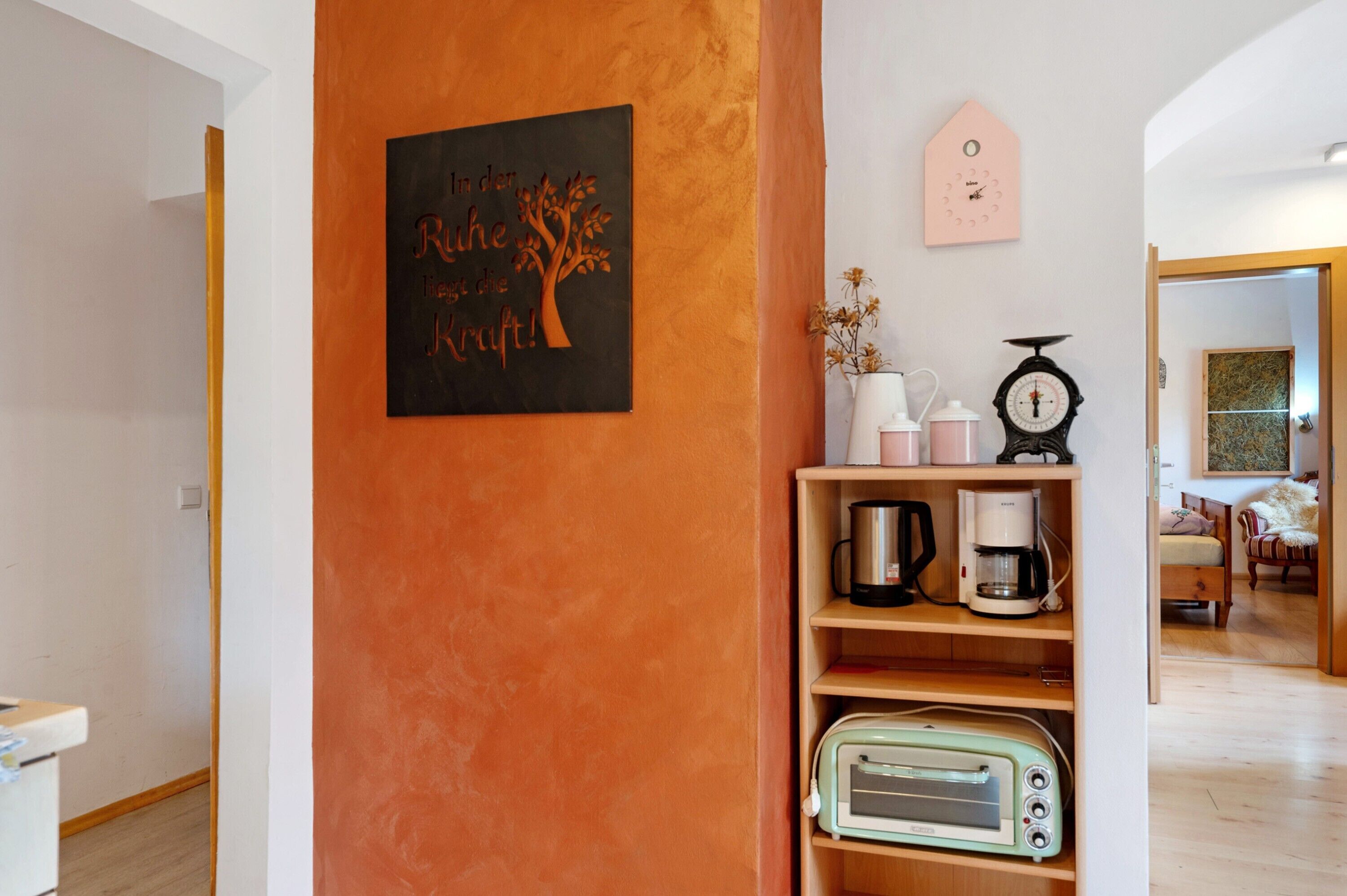 A kitchen area with a coffee maker, toaster, and a clock on the wall.