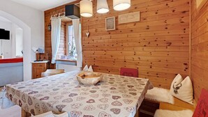 Un interior de madera con una mesa de comedor, sillas, un cuenco y un televisor montado en la pared.