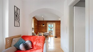 Una habitación con techo de madera, un comedor y un sofá con una manta roja.