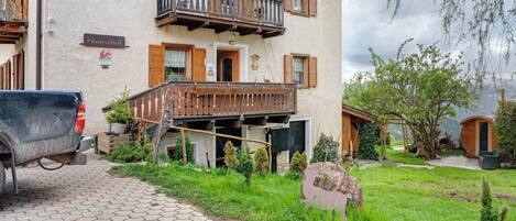 Un edificio a più piani con un balcone, un camion parcheggiato e un giardino curato.