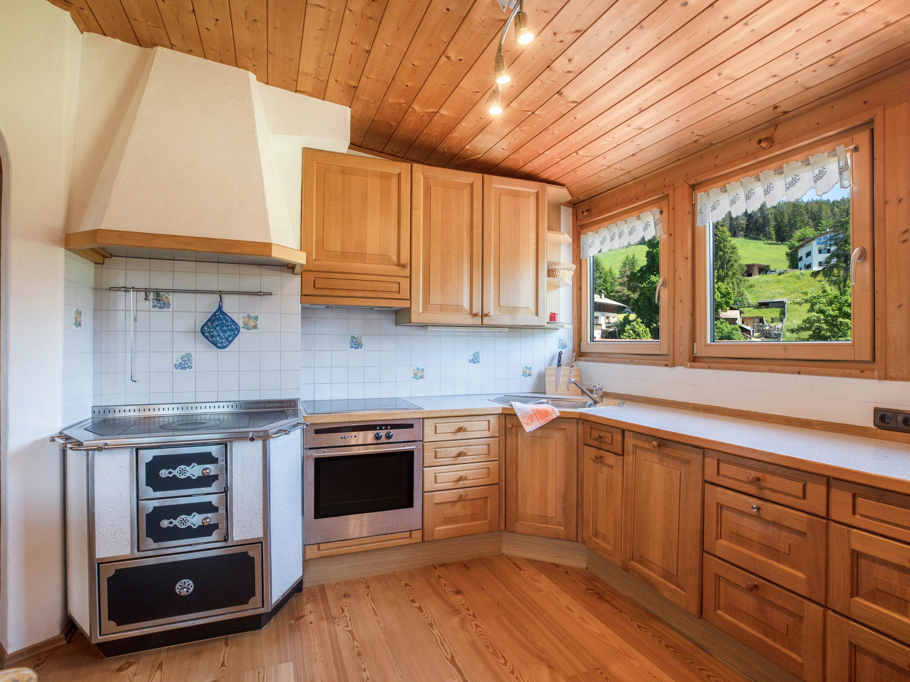 Una cucina con mobili in legno, un fornello, un forno e una finestra vista verde.
