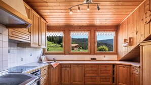 Eine Küche mit Holdekor, einem Herd und einem Fenster mit Blick auf eine grüne Landschaft.