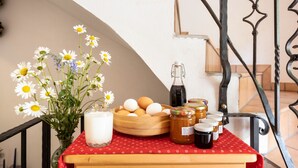 Et bord med et rødt dug, en blomstervase, æg, honningsglas og en mælkeflaske.
