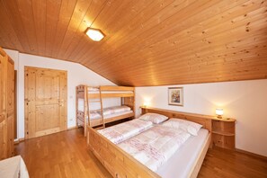 A wooden bunk bed room with a sloped ceiling, wooden walls, and a wooden door.