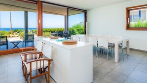 Una cocina moderna con una isla grande, comedor y vistas al océano.