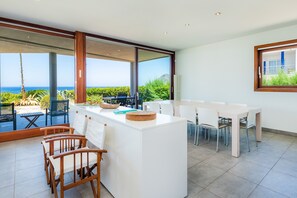 A modern kitchen with a large island, dining area, and a view of the ocean.