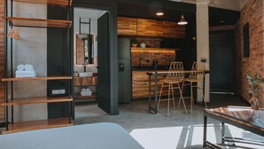 A modern kitchen with wooden cabinets, a built-in oven, and a dining area with a table and chairs. - Industrial Chic Loft in Front of Unicentro Mall (Medellín)