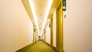 A hotel corridor with a green carpet, multiple doors, and overhead lighting. - Greentree Inn Chuzhou Langya Mountain Scenic Area Xijian Road (Chuzhou)