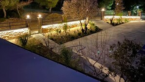 Un espacio al aire libre bien iluminado con un sendero pavimentado, muros de piedra y árboles.